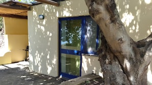 Un bâtiment avec une porte bleue, un arbre devant et un chemin en béton.