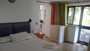 Une chambre à coucher comprenant un lit, une table de chevet, une commode et une fenêtre avec des rideaux.