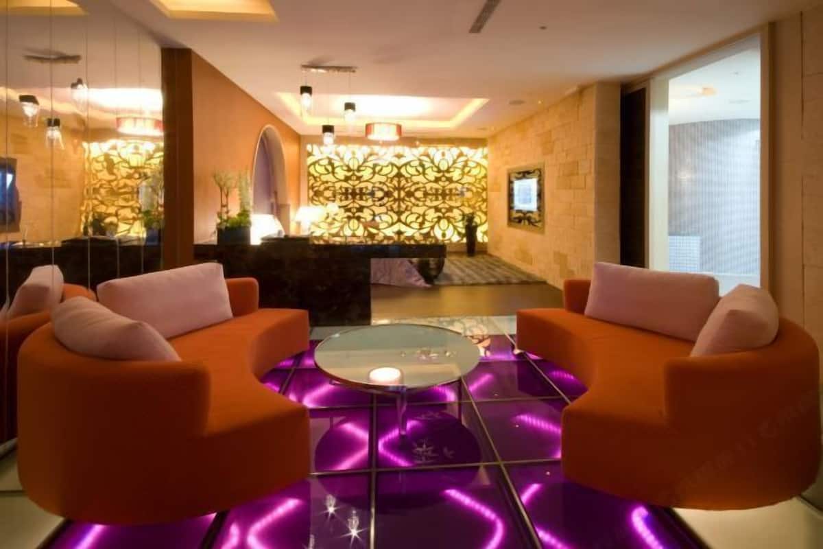 Een moderne lobby met oranje zitplaatsen, een glazen salontafel en een decoratieve wand.