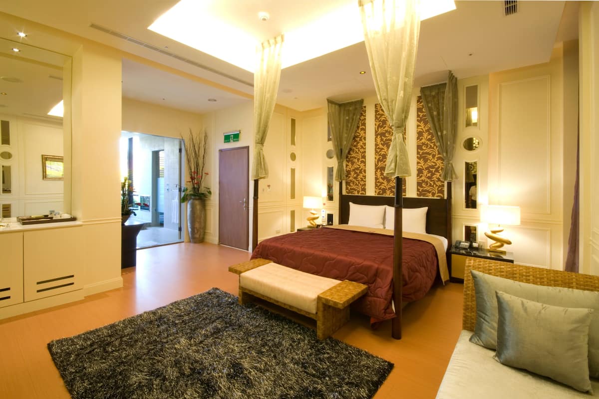 Een ruime hotelkamer met een groot bed, een zithoek en uitzicht op de gang.