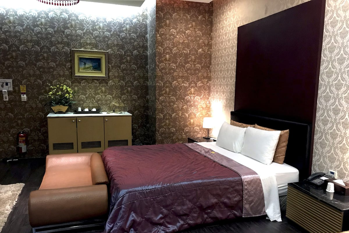 Een hotelkamer met een bed, een bureau, een stoel en een nachtkastje.