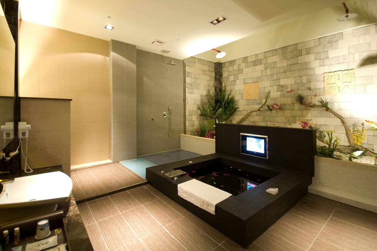 Een moderne badkamer met een badkuip, douche en een digitaal scherm.