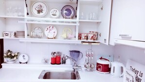 A kitchen with white cabinets, a stainless steel sink, and various kitchenware.