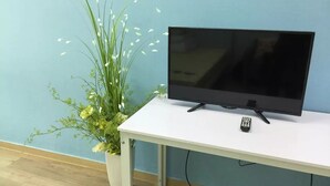 A white TV stand with a flat-screen TV and a remote control.