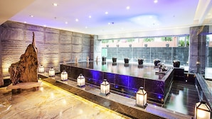 Un baño moderno con piso de mármol, una escultura de madera y una fila de faroles iluminados.