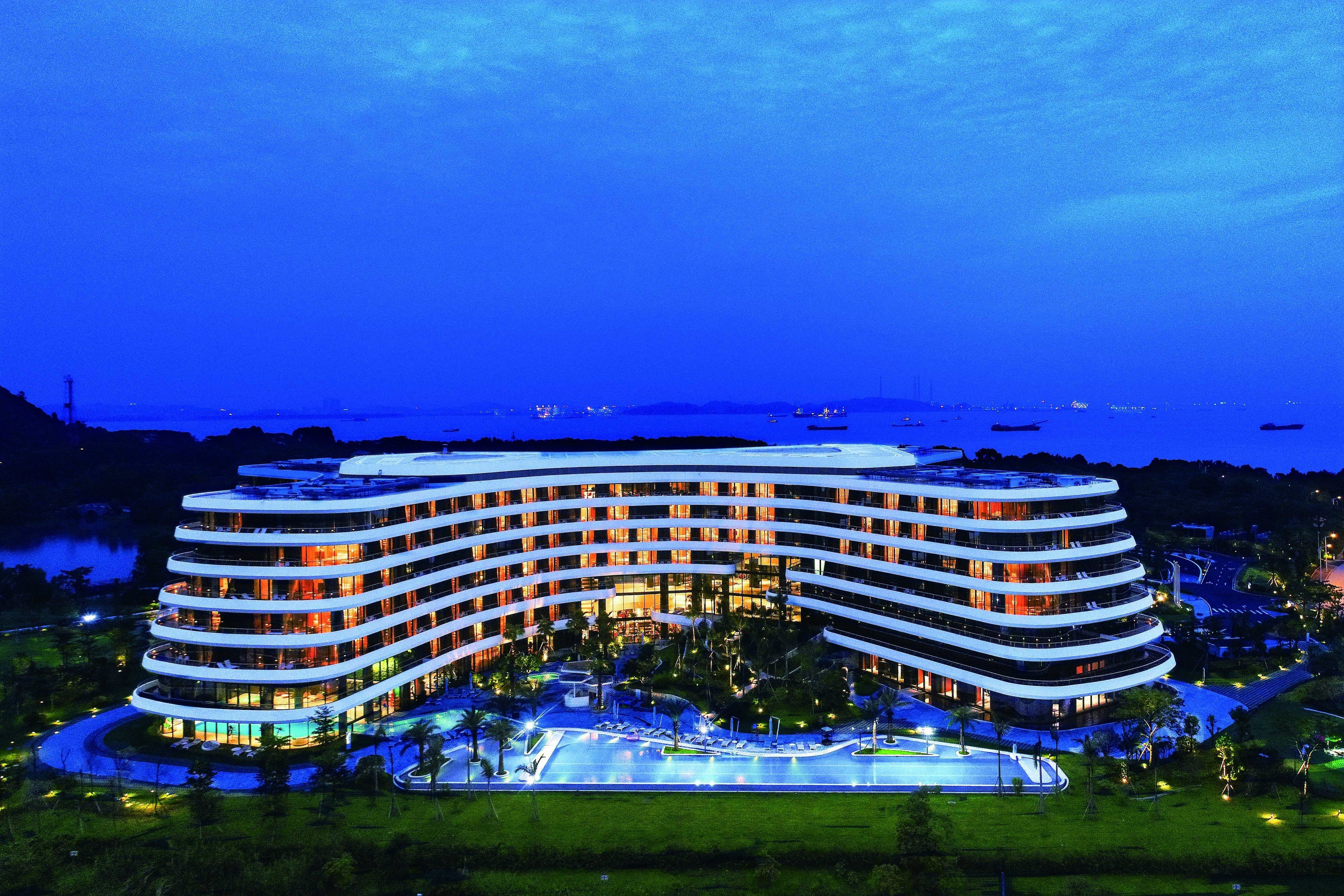 Et moderne hotel med flere etager, en central gårdhave og et poolområde.