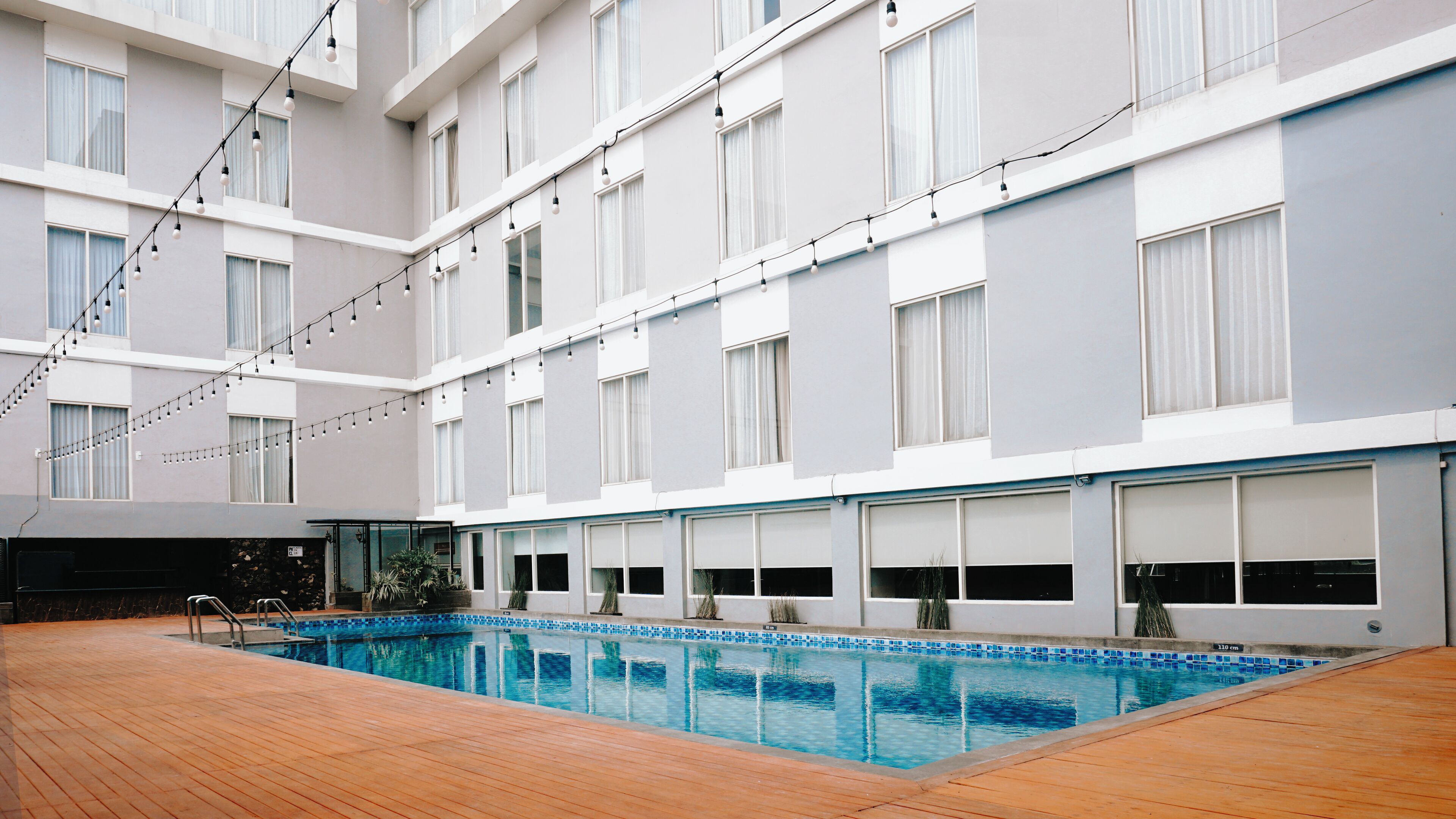 Un hotel modern amb una gran piscina interior, múltiples balcons i llums lluminoses.