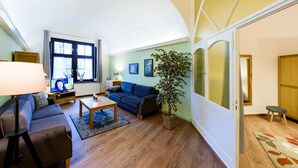 Un salon avec un canapé, une table basse, un téléviseur et une plante.