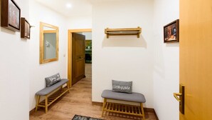Un couloir avec des bancs en bois, un miroir et des tableaux encadrés accrochés aux murs.