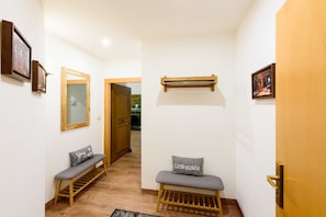 A hallway with wooden benches, a mirror, and framed pictures on the walls.