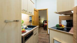 Una cocina compacta con armarios de madera, lavavajillas y una pequeña encimera con un bol de fruta.