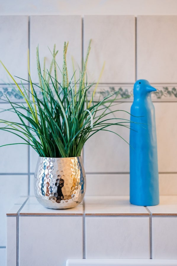 A potted plant with green foliage and a blue water bottle on a tiled surface.