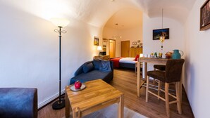 Un espacio habitable compacto con un sofá, una mesita, una silla y una cama.