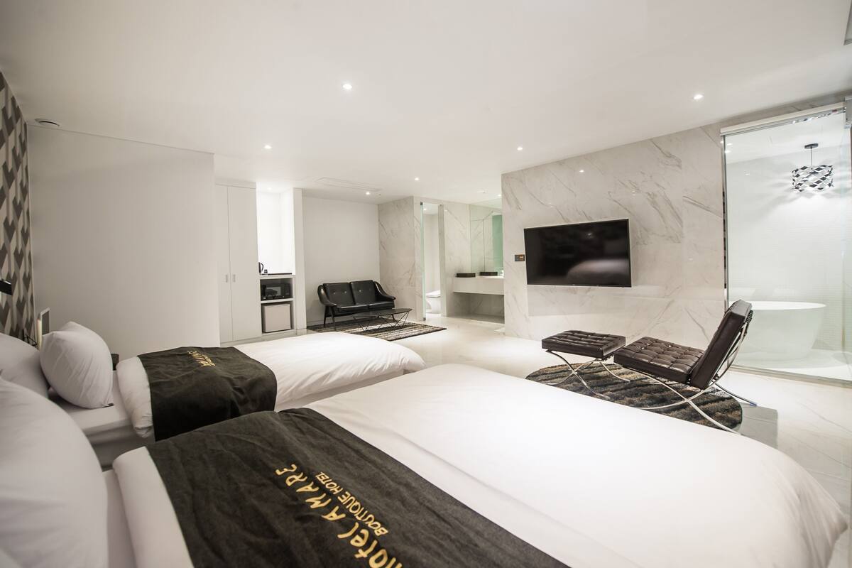 Une chambre d’hôtel moderne équipée de deux lits, d’une télévision, d’un bureau et d’un espace douche.
