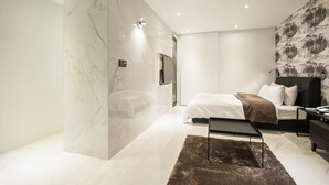 A modern bedroom with a large bed, a bedside table, a nightstand, and a wall-mounted TV. - Hotel AMARE (Suwon)