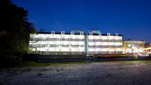 Un hotel de varios pisos con un diseño moderno, con balcones en cada planta y una fachada bien iluminada.