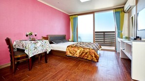 Una habitación de hotel con cama, escritorio, silla, balcón con cortinas y televisión.