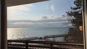Vista de una zona costera con un muelle de madera que se adentra en el agua, una playa de arena y un cielo despejado con nubes.
