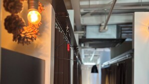A narrow hallway with a wooden floor, a wall-mounted light fixture, and a door at the end. - Chillulu Coffee & Hostel (Yokohama)