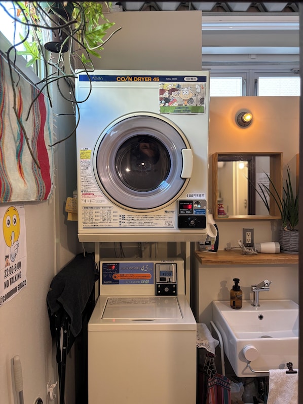Ein kleiner Waschbereich mit einer Waschmaschine mit Frontlader, einem kleinen Spülbecken und einem Spiegel darüber.