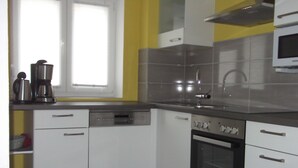 Een moderne keuken met witte kastjes, een inbouwoven en een magnetron.