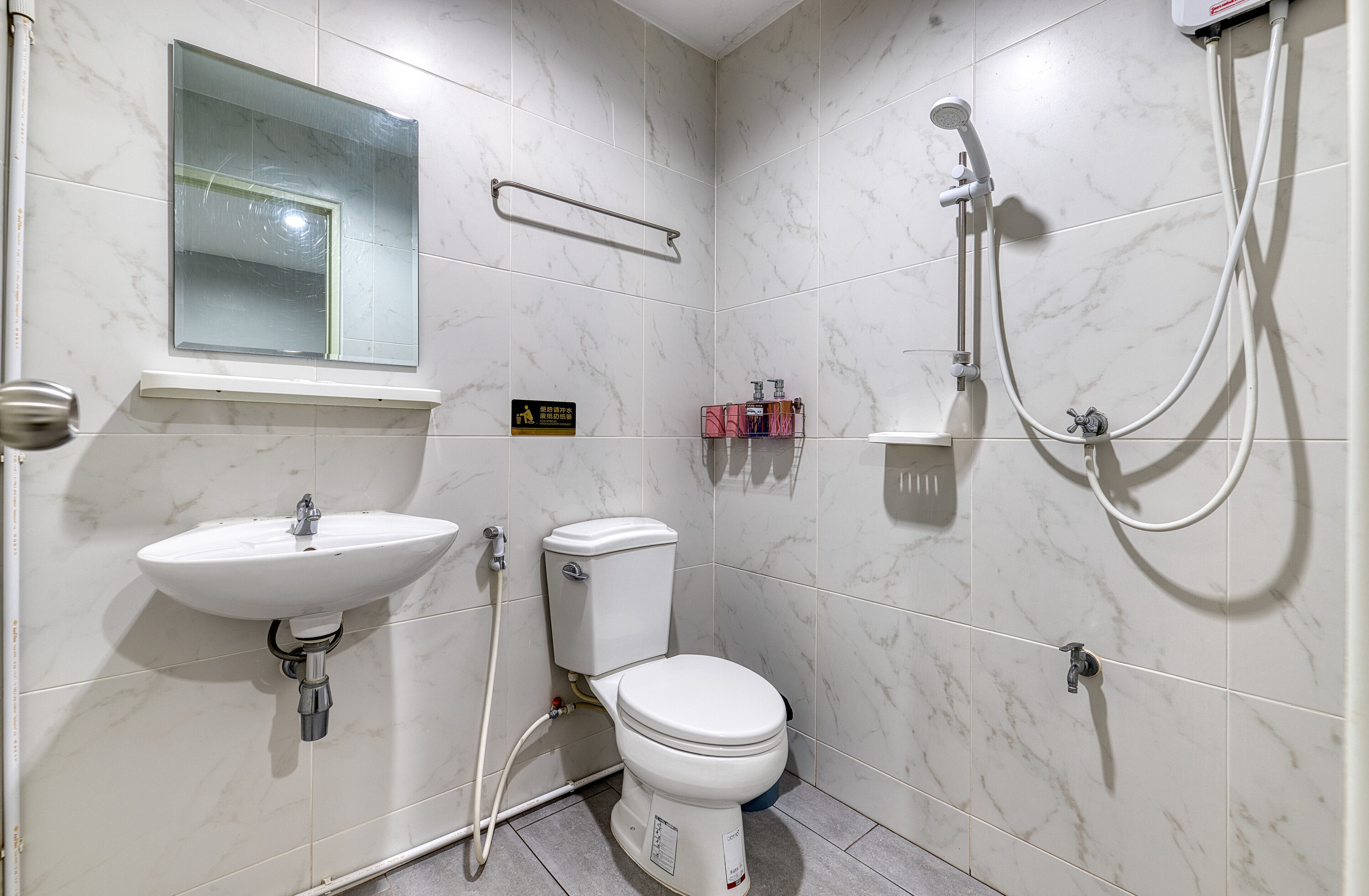 A bathroom with a toilet, sink, and shower.