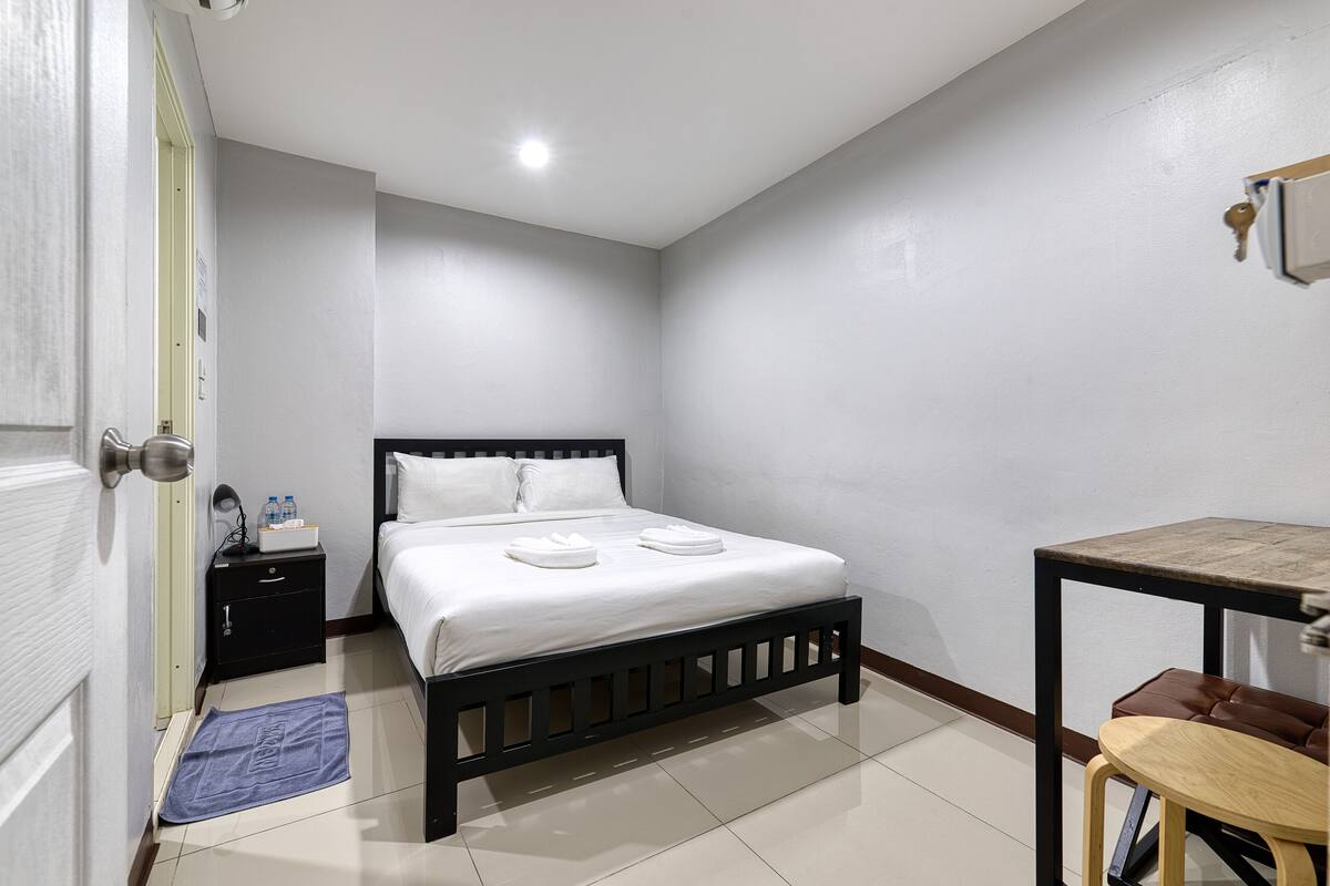 Une chambre à coucher avec un lit, une table de chevet et un petit bureau avec une chaise.