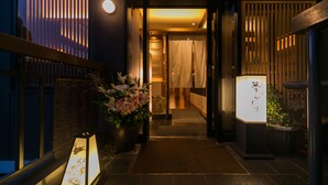 Un couloir au décor d’inspiration japonaise traditionnelle, comprenant une lanterne, une plante en pot et une porte coulissante.