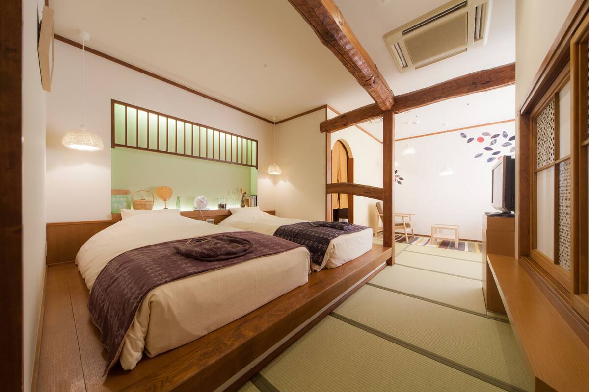 A traditional Japanese-style room with tatami flooring, a low wooden bed frame, and a sliding door leading to a balcony.