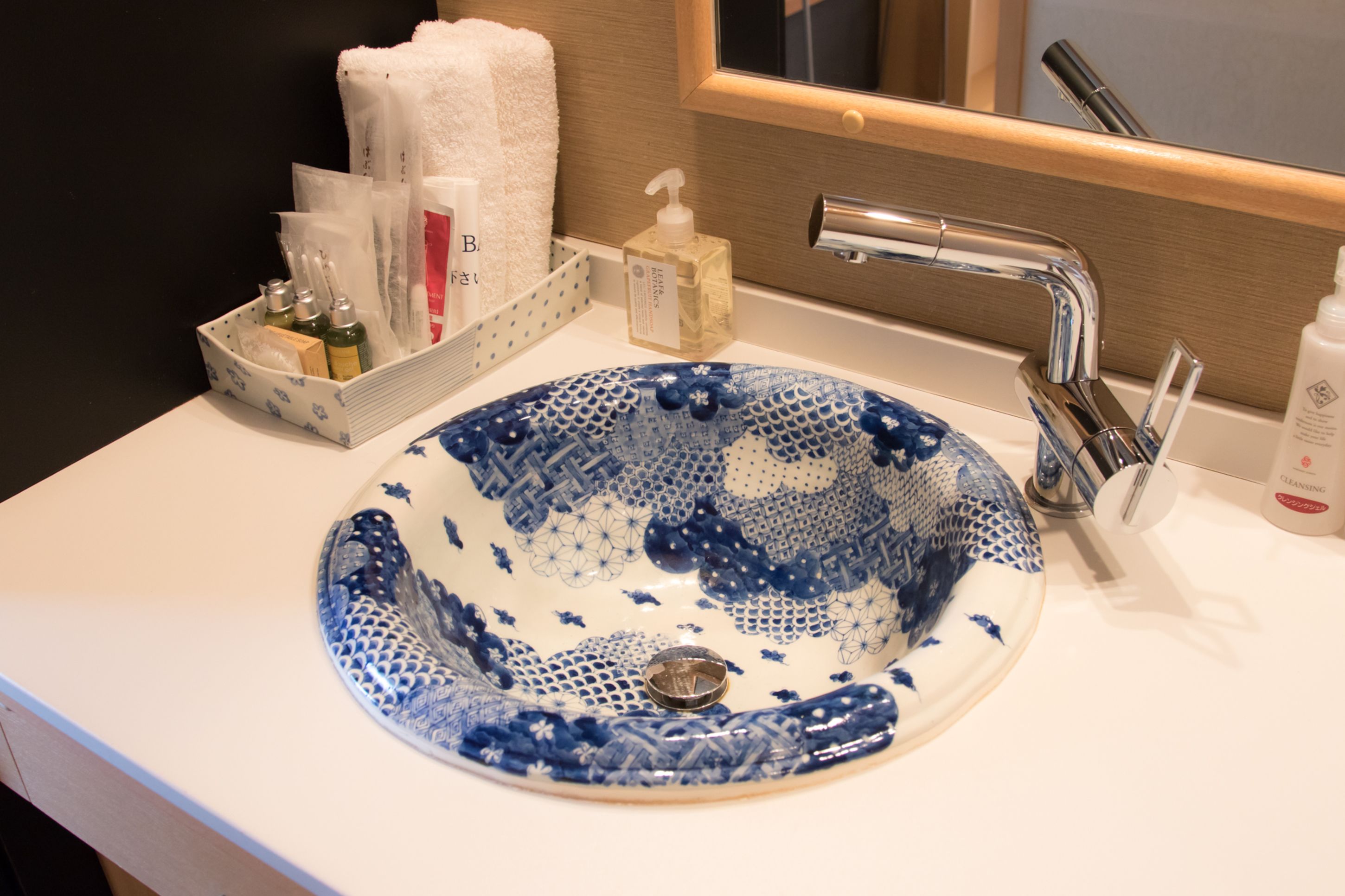 A bathroom with a blue ceramic sink, a white towel, and toiletries.