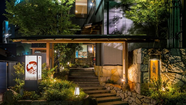 Un bâtiment traditionnel japonais avec un escalier en pierre menant à une entrée en bois.