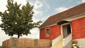 A red building with a stone wall, wooden fence, and a staircase leading to the entrance.
