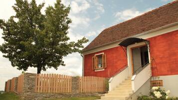 A red building with a stone wall, wooden fence, and a staircase leading to the entrance.
