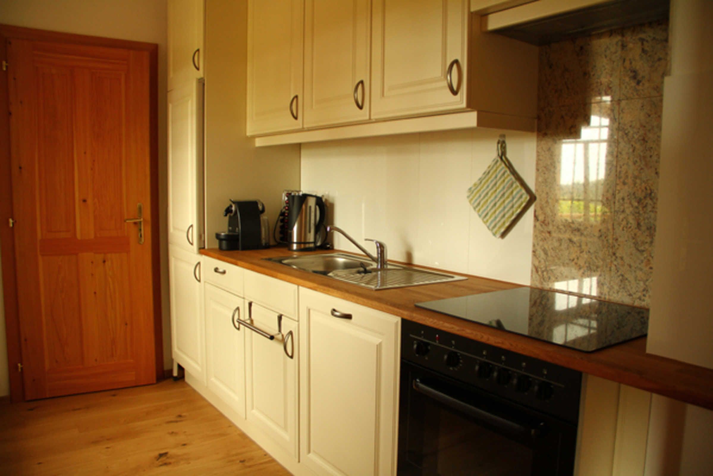 A kitchen with wooden cabinets, a stainless steel sink, a stove, and a granite countertop.