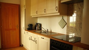 A kitchen with wooden cabinets, a stainless steel sink, a stove, and a granite countertop.