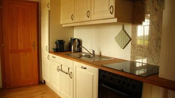 A kitchen with wooden cabinets, a stainless steel sink, a stove, and a granite countertop.