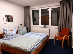 A bedroom with a bed, a chair, a window, and a radiator. - Damerow Dünenstraße - Holiday apartment (Zinnowitz)