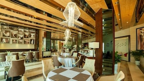 Een moderne hotel lobby met een ronde centrale tafel, meerdere zithoeken en een grote kroonluchter.