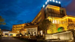 Een hotel met een modern design, met een opvallend bord met Chinese karakters, meerdere verdiepingen en een goed verlichte ingang.