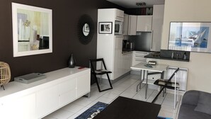 A modern kitchen with white cabinets, a black-framed mirror, and a dining area with a black table and two chairs. - Apartment with direct beach access (parking, Wi-Fi, near downtown)—check out the reviews! (Arcachon)