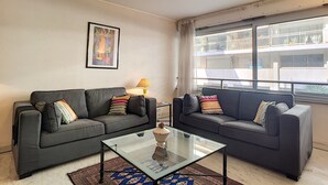 A modern living room with two grey sofas, a glass coffee table, and a framed artwork on the wall. - N&J - MARIN DEBUSSY - Hyper center (Niza)