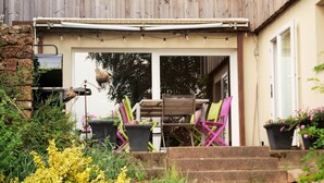 A house with a covered patio, outdoor seating, and steps leading to the entrance.
