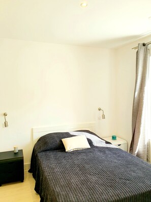 A bedroom with a bed, bedside tables, and a nightstand. - SEASIDE APARTMENT WITH HEATED POOL (Galéria)