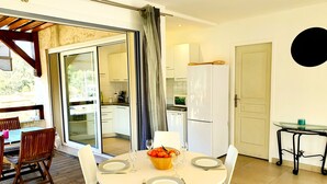 A dining area with a table set for four, a kitchen in the background, and a sliding glass door leading to an outdoor space. - SEASIDE APARTMENT WITH HEATED POOL (Galéria)