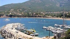 A coastal marina with boats docked, a rocky breakwater, and a mountainous backdrop. - SEASIDE APARTMENT WITH HEATED POOL (Galéria)