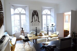 Een eetruimte met een houten tafel, witte stoelen en een groot raam.