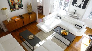 Una sala moderna con un sofá blanco, un mueble de madera y una mesa de centro con frutas.