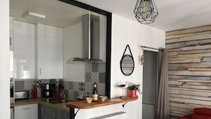 Een kleine keuken met witte kasten, een inbouwfornuis en een rode fles op het aanrecht.