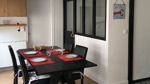 Een eethoek met een zwarte tafel gedekt voor vier personen, rode placemats en zwarte stoelen.