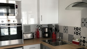 Een moderne keuken met witte kasten, roestvrijstalen apparatuur, een patroon backsplash en een houten aanrecht.